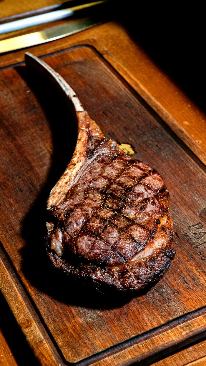 Juicy grilled tomahawk steak on a rustic wooden board, perfect for gourmet grilling themes.